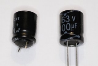 Two electrolytic capacitors: the one on the left is inflated compared to a new one on the right. No need to measure: an inflated capacitor must be replaced.